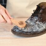 Man cleaning leather shoe with saddle soap and dauber brush, illustrating Saddle Soap vs Leather Conditioner comparison