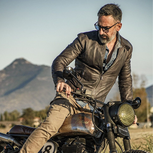 Man riding a bike wearing a leather jacket, raising the question can leather jackets be dry cleaned and discussing how to clean a leather jacket, how to spot clean a leather jacket, and proper leather jacket care.