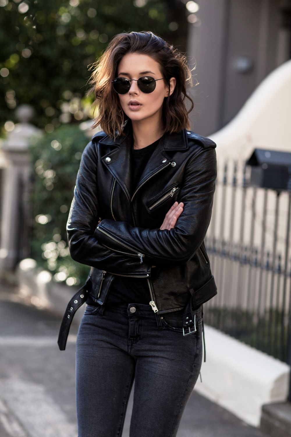 lt Text:"Women wearing an all-black outfit, featuring a classic black biker leather jacket, paired with black jeans and boots, exuding edgy sophistication