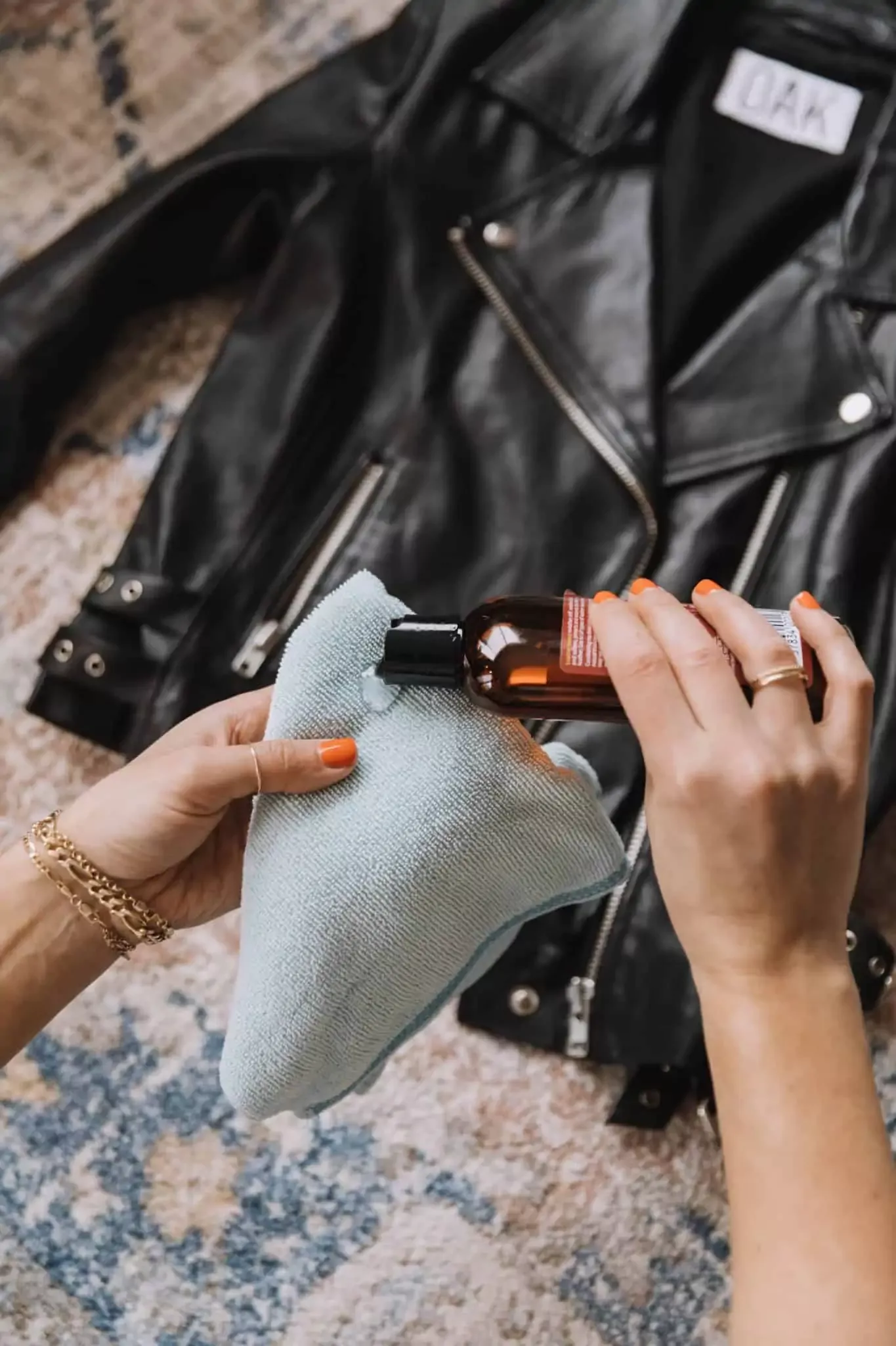 Person gently cleaning a leather jacket lining with a soft cloth and mild soap solution, demonstrating how to clean a leather jacket lining